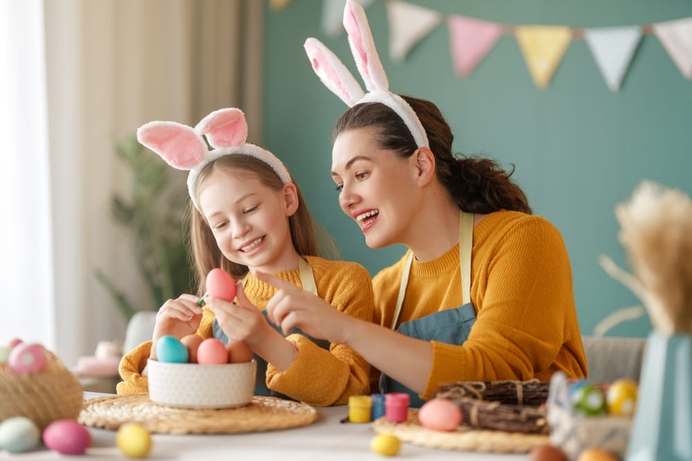 Mother and her daughter painting eggs. happy family preparing